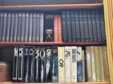 une bibliothèque sur laquelle sont rangés de nombreux livres, avec une horloge posée dessus