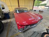 une voiture rouge garée dans un garage, à côté d'un chien