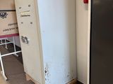 a white refrigerator in the corner of a room next to a black door