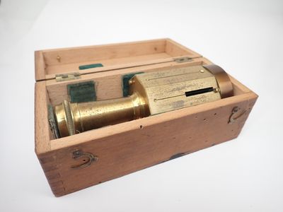 une vieille boîte en bois contenant un télescope, posée sur une surface blanche
