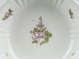 a white bowl with pink flowers on it on a table