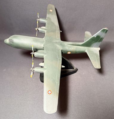 une maquette ancienne d'un avion militaire posée sur une surface grise