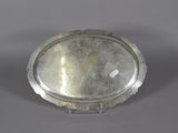 an antique silver plate with a metal rim on a gray surface