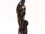 une statue en bronze représentant une femme tenant un chien, sur fond blanc