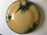 une assiette jaune ornée d'un motif vert et noir