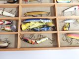many different types of fishing lures in a wooden box