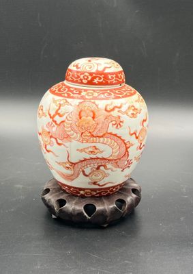 an orange and white vase sitting on top of a metal stand
