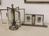 a silver clock sitting on top of a table next to a picture frame