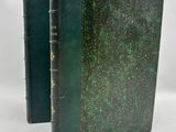 an old book with a green cover sitting on top of a white table