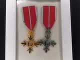 Deux médailles sont exposées dans un cadre vitré posé sur une table