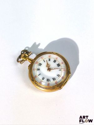 une petite montre de poche en or avec des chiffres romains