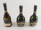 three bottles of champagne sitting next to each other on a white surface