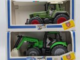 two toy tractors in a box on a white surface