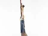 a figurine of a woman climbing a tree with a stick