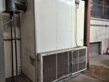 un grand réfrigérateur blanc dans un immeuble où il y a beaucoup de tuyaux