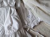 a white dress laying on top of a bed next to a pair of shoes