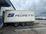 un grand camion blanc garé devant un immeuble