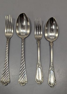 quatre cuillères en argent et une fourchette sont alignées sur une table