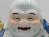a statue of a laughing buddha with a bird on his shoulder