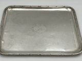un plateau ancien en argent posé sur une table blanche, muni d'une poignée en argent