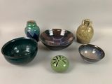 de nombreux bols et vases de toutes sortes posés sur une table