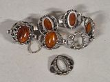 two pieces of silver and amber jewelry on a white surface