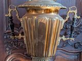 a gold vase sitting on a black table in front of a wooden paneled wall