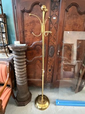 un grand lampadaire en laiton à côté d'un grand meuble en bois