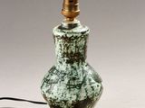 a green and white lamp with a black cord on top of it