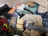 a pile of clothes on the floor next to a bed