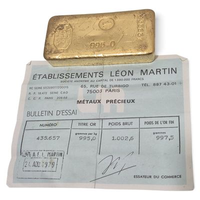 un morceau d'or posé sur une feuille de papier sur laquelle est représenté un lingot d'or