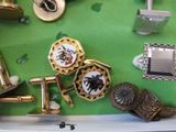 many different types of cufflinks on a green table