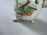 a white vase with a painting on it sitting on a table