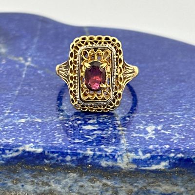 an image of a gold ring with a red stone