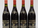 four bottles of wine are lined up on a white surface