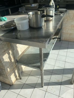 a stainless steel table with pots and pans on it