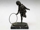 statue en bronze représentant un garçon tenant une raquette de tennis, posée sur un socle en marbre