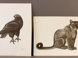 two paintings of a cat and a bird on a table