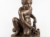 une statue antique en bronze représentant un garçon avec des raisins