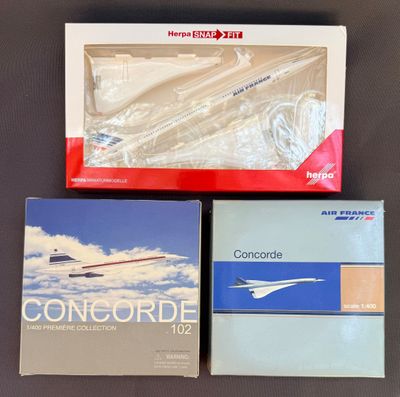 trois livres dans leur boîte posés sur une table, avec un avion en arrière-plan