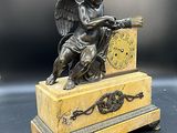 une figurine antique en bronze représentant un ange avec une horloge