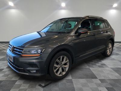 une Volkswagen Tiguan grise garée dans un showroom au sol carrelé