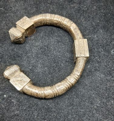 gros plan d'un bracelet en or sur une surface noire