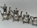 trois théières en métal argenté et un pichet sur fond blanc
