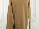 a brown sweater on a mannequin stand in front of a white wall