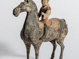 une vieille figurine représentant un homme à cheval avec un enfant sur le dos