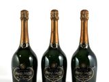 trois bouteilles de champagne posées les unes à côté des autres sur une surface blanche