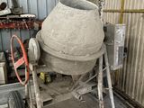 une bétonnière rangée dans un garage, dont une roue repose sur un chariot