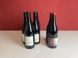 three bottles of wine sit on a table in front of a red wall