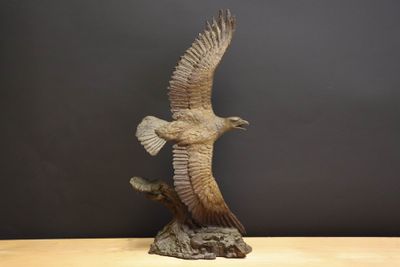une image représentant une statue d'un oiseau en plein vol au-dessus d'une table en bois